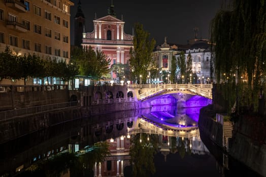Famous three bridges at the Preseren square in the center of Ljubljana colorfully illuminated at night, Slovenia
