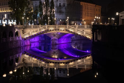 Famous three bridges at the Preseren square in the center of Ljubljana colorfully illuminated at night, Slovenia
