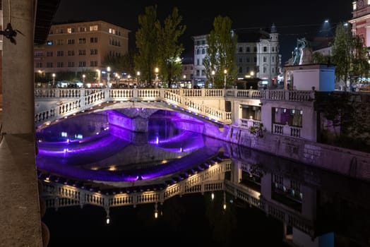 Famous three bridges at the Preseren square in the center of Ljubljana colorfully illuminated at night, Slovenia