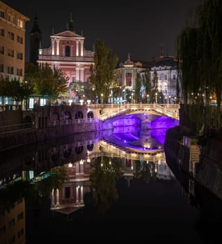 Famous three bridges at the Preseren square in the center of Ljubljana colorfully illuminated at night, Slovenia