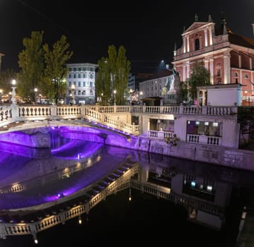 Famous three bridges at the Preseren square in the center of Ljubljana colorfully illuminated at night, Slovenia