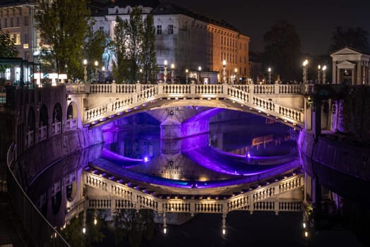 Famous three bridges at the Preseren square in the center of Ljubljana colorfully illuminated at night, Slovenia