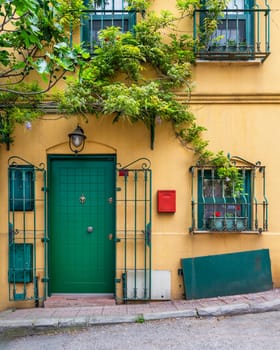 Charming yellow house with a green door and windows, surrounded by climber plants and flowers, located in an alley suited in Kuzguncuk quiet neighborhood, Uskudar district, Istanbul, Turkey