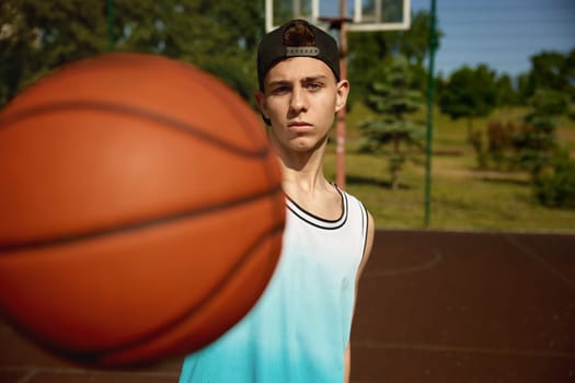 Closeup shot of teenager basketball player holding ball front of camera. Sport activity and youth