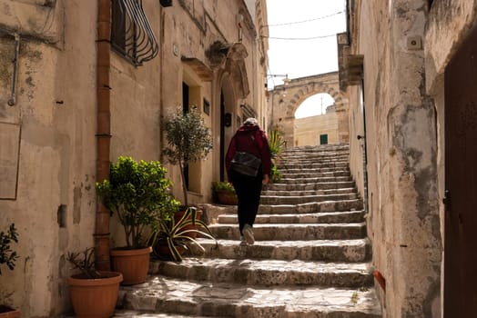 A female person walking up a stairway in downtown Matera, Southern Italy