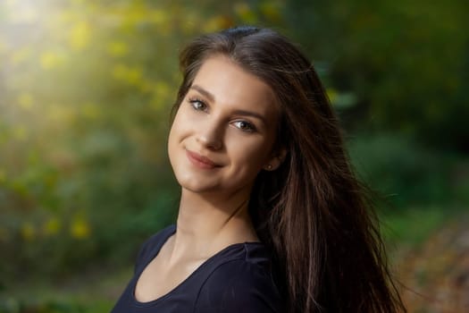 Portrait of attractive young brunette woman posing outdoors in autumn. Horizontally.