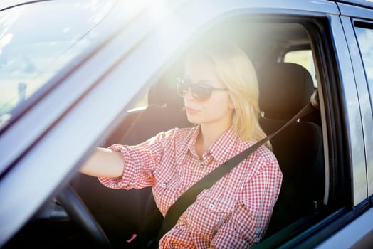 Happy young woman driver driving her new luxury car. Summer roadtrip travel and people lifestyle concept.