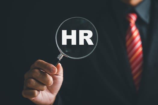 Unlocking HRM potential Magnifier glass highlights manager icon in staff icons, representing power of human resource management in recruitment, leadership, employee development. employees selection