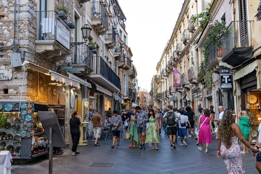 Giardini Naxos Sicily Italy  08.07.2022 - Tourists walking in the afternoon on an alley full of people and shops