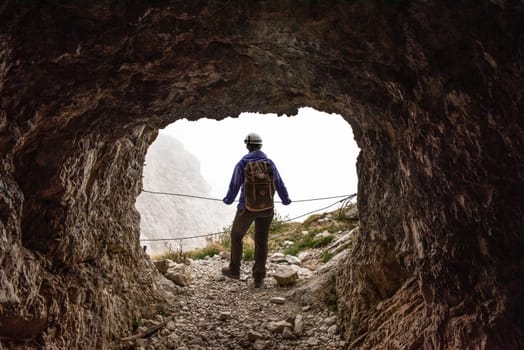 A hiker enjoying the view out of an old military tunnel at Mount Lagazuoi, autonomous province of South Tirol