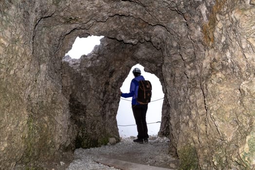 A hiker enjoying the view out of an old military tunnel at Mount Lagazuoi, autonomous province of South Tirol