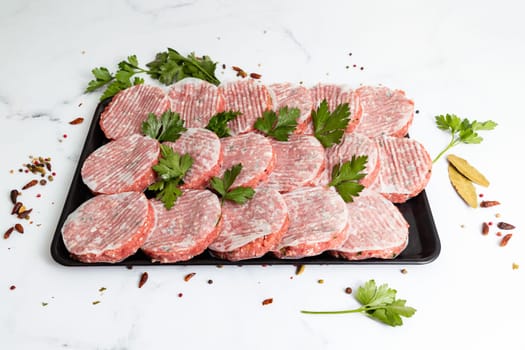 Fresh hamburger patties on a plate with parsley