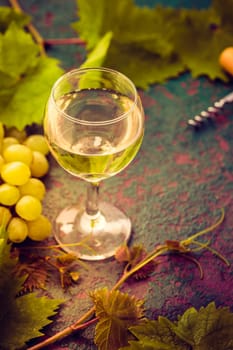 Still life with glass of white wine with grapes and bottle opener