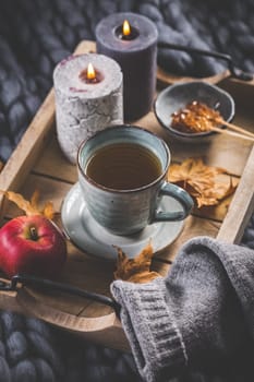 Autumn mood concept. Warm, cozy and rustic still life with cup of tea, candle and pumpkins.