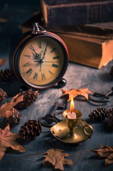 Vintage still life with  antique  books, clock and candle. Halloween and occult concept.