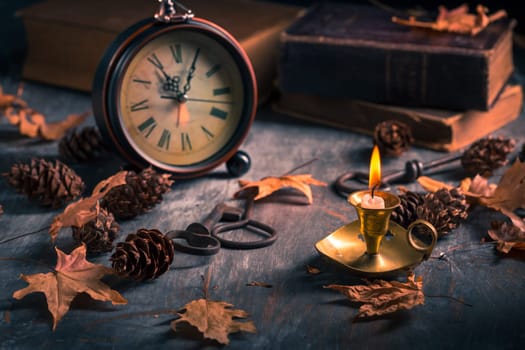 Vintage still life with  antique  books, clock and candle. Halloween and occult concept.