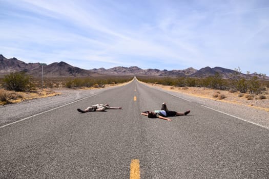 Two people pretending to lay dead on a highway in the Death Valley, USA