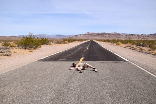 A man pretending to lay motionless in the middle of a highway in the Death Valley, USA