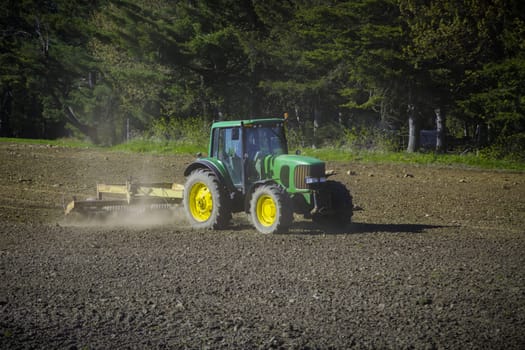 A serene rural landscape captured as a tractor effortlessly plows through a vast field, harmonizing nature and agriculture.