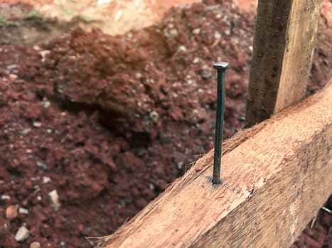 Concrete nails that are driven into the chart wood to tie ropes that will be used to find the width and length of the area for use in construction blurred background
