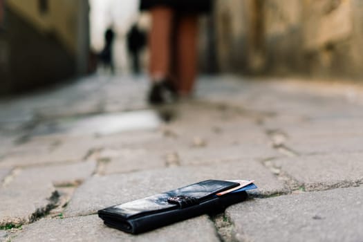 Photo of the sidewalk and legs of man who lost a black leather wallet while walking