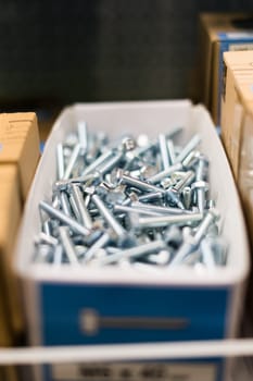 Small thin metal nails, hardware, screw lying in store container.