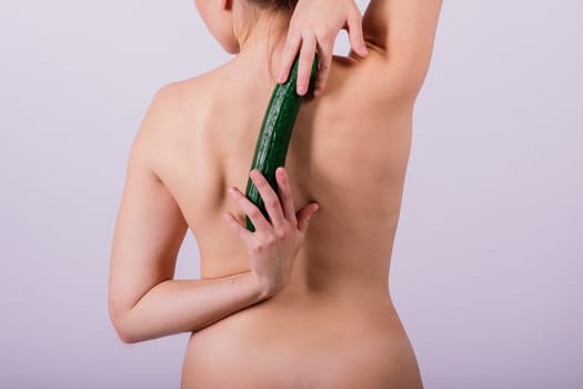 Woman female topless body standing isolated over white background with a cucumber