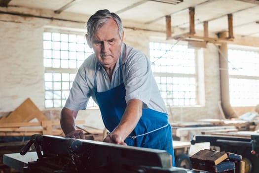 Experienced master carpenter working with wood milling machine in his vintage workshop