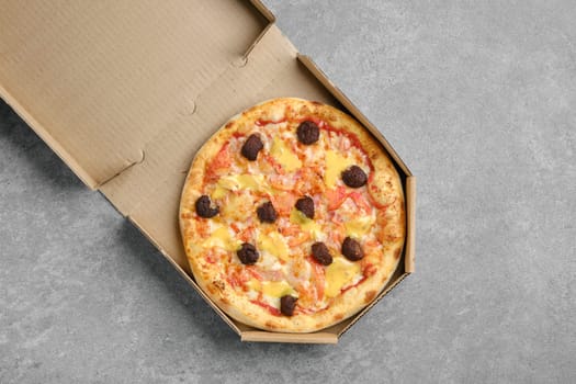 Top view of pizza with beef meatballs, cheddar and tomato slices in cardboard box