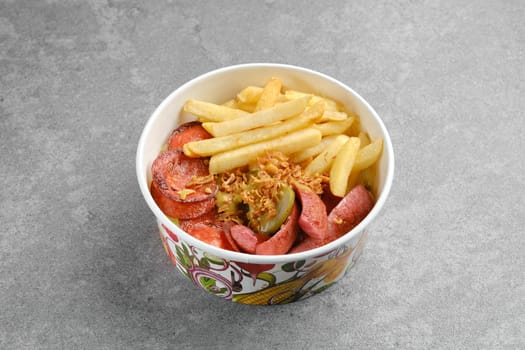 Takeaway snack or lunch in cardboard bowl. Sausage, french fries and pickled cucumber