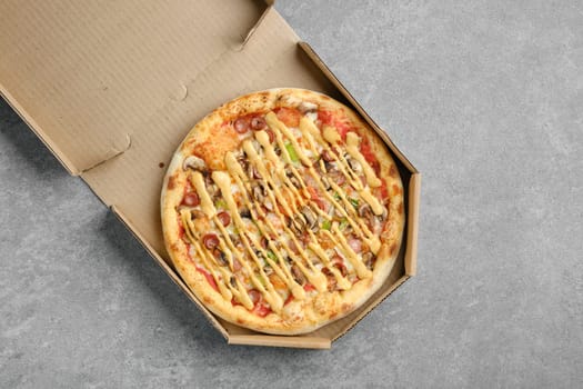 Top view of pizza with thin sausage, jalapeno and champignon in cardboard box
