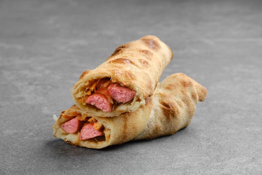Thin sausage rolled and baked in dough with cabbage, carrot and cheese cut on half