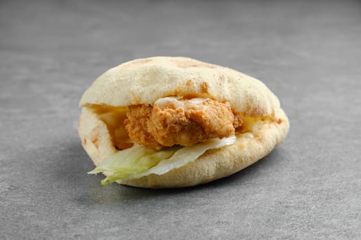 Flat bread with chicken fillet in breading, iceberg lettuce and melted cheese