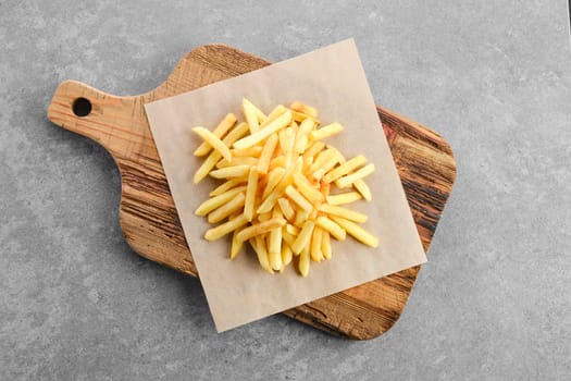 Top view of portion of salty french fries on paper
