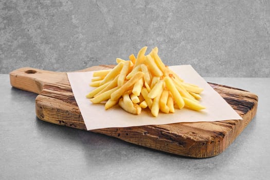 Portion of salty french fries on parchment paper