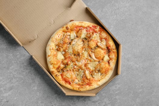 Top view of pizza with chicken, cheese and pineapple in cardboard box