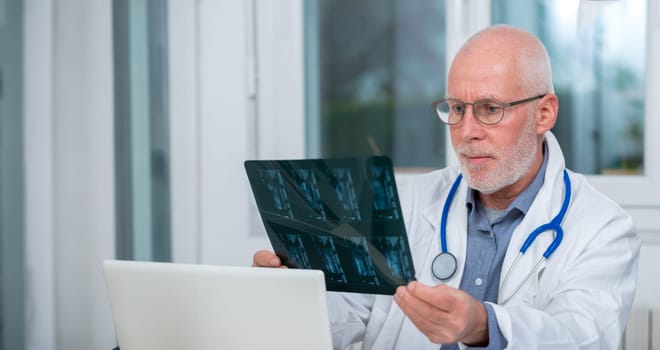 a mature Doctor looking at an x-ray in an office