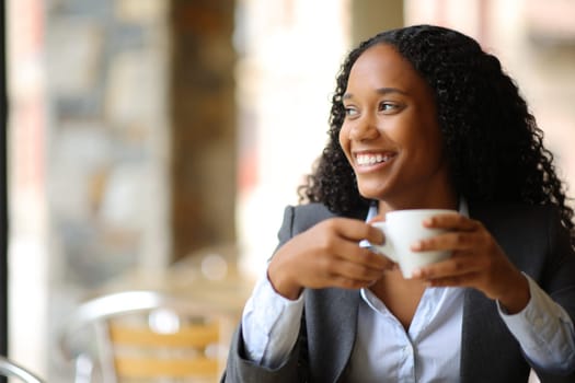 Happy black executive looking at side in a coffee shop terrace