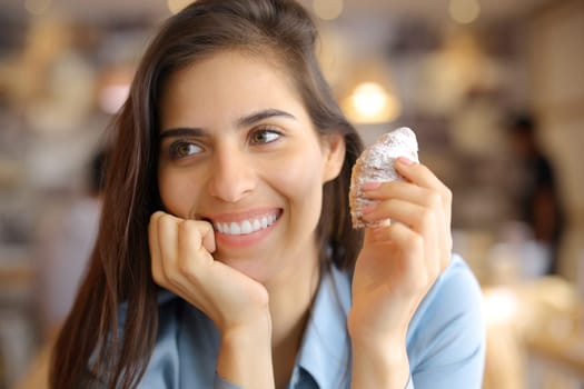 Happy woman with beauty smile holding croissant in a bar interior