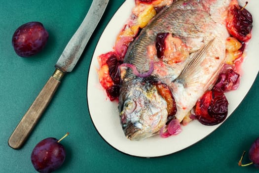 Dorado or sea bream fish baked with plums.