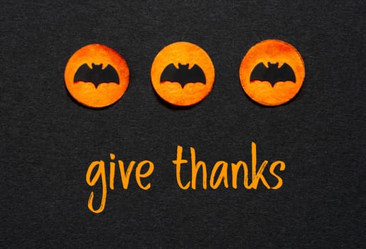 Black Halloween Background With Three Orange Dots With Bats And Text Give Thanks