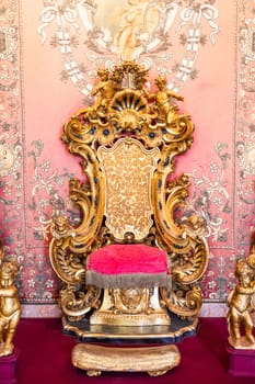 Isola Bella, Italy - 1 August 2023: antique throne in gold and red velvet. Old royal chair, luxury vintage.