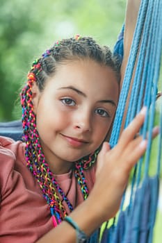 Closeup portrait of young girl with colorful braids in her hair smiling at the camera closeup.  Vertically.