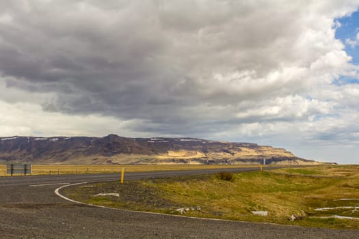 Road to Seljalandsfoss waterfall, the waterfall small in the background, Iceland