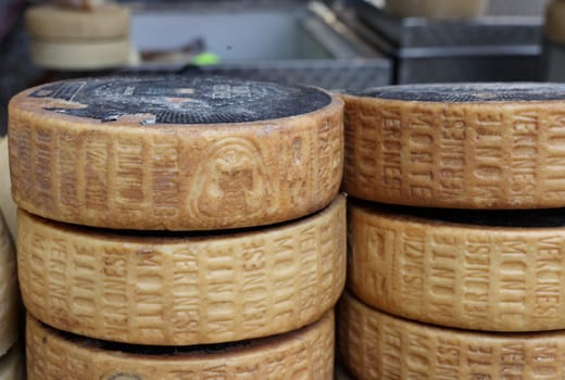 Cremona, Italy - September 7, 2022: Whole wheels of Monte Veronese cheese sold at a street stall during the farmers market in Cremona, Lombardy, Italy