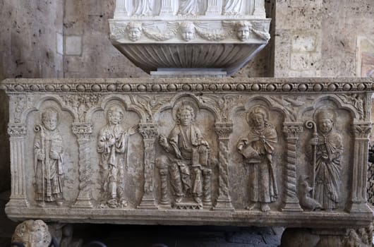 Massa Marittima, Italy - Sept 11, 2022:  Monumental baptismal font, with a rectangular bath surmounted by a small temple. The baptistery dates from 1267. Cathedral of Saint Cerbonius in Massa Marittima. Italy