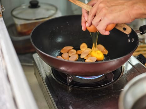Cooking of sausage fried rice and crack an egg with mixed vegetable .