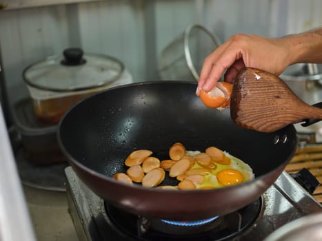 Cooking of sausage fried rice and crack an egg with mixed vegetable .