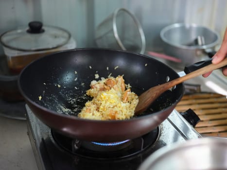 Cooking of sausage fried rice and crack an egg with mixed vegetable .