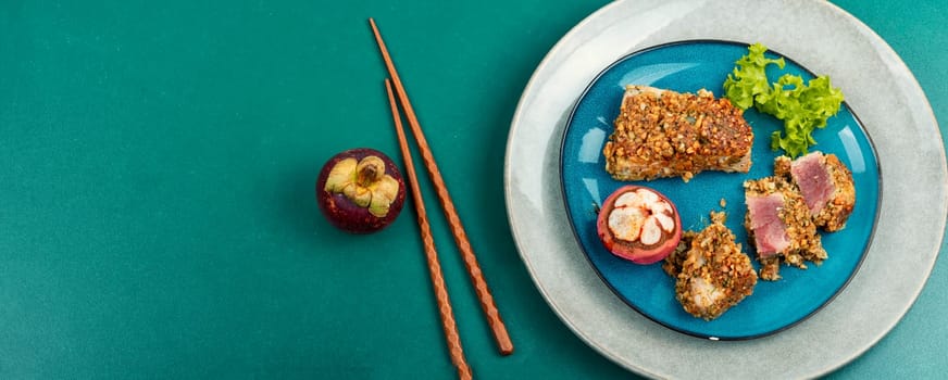 Steak of baked tuna fillet in a nut panic with a mangosteens. Space for text. Long banner.